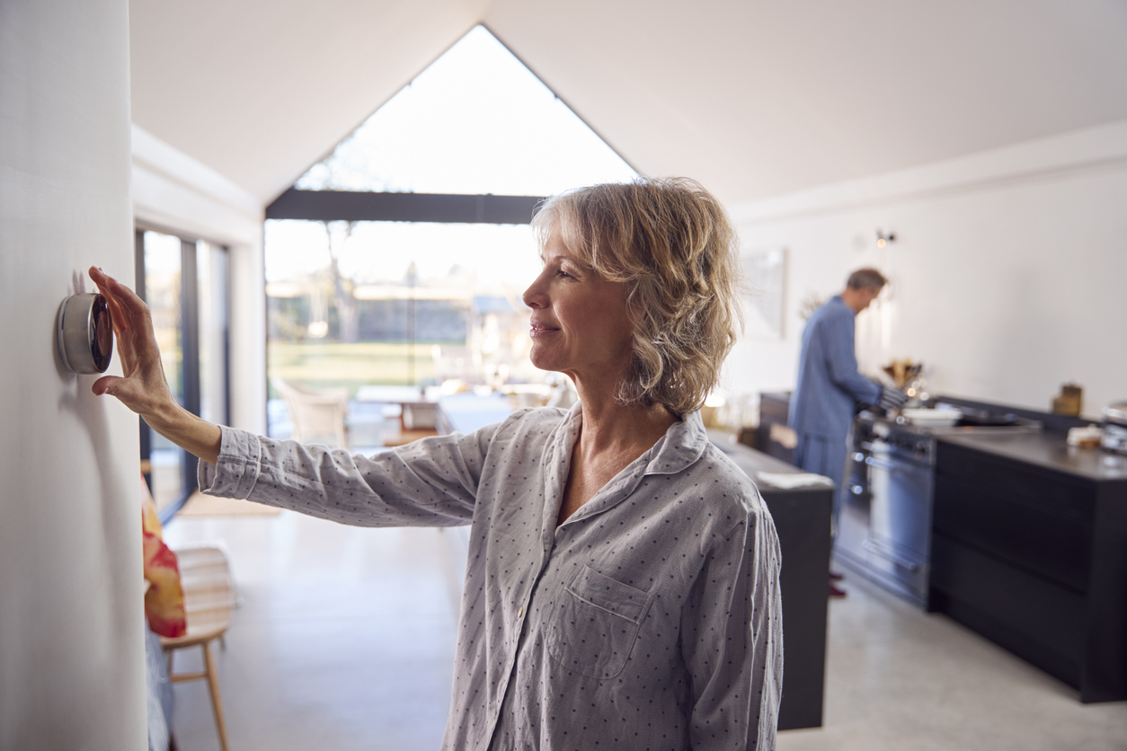 Mature woman adjusting home smart thermostat