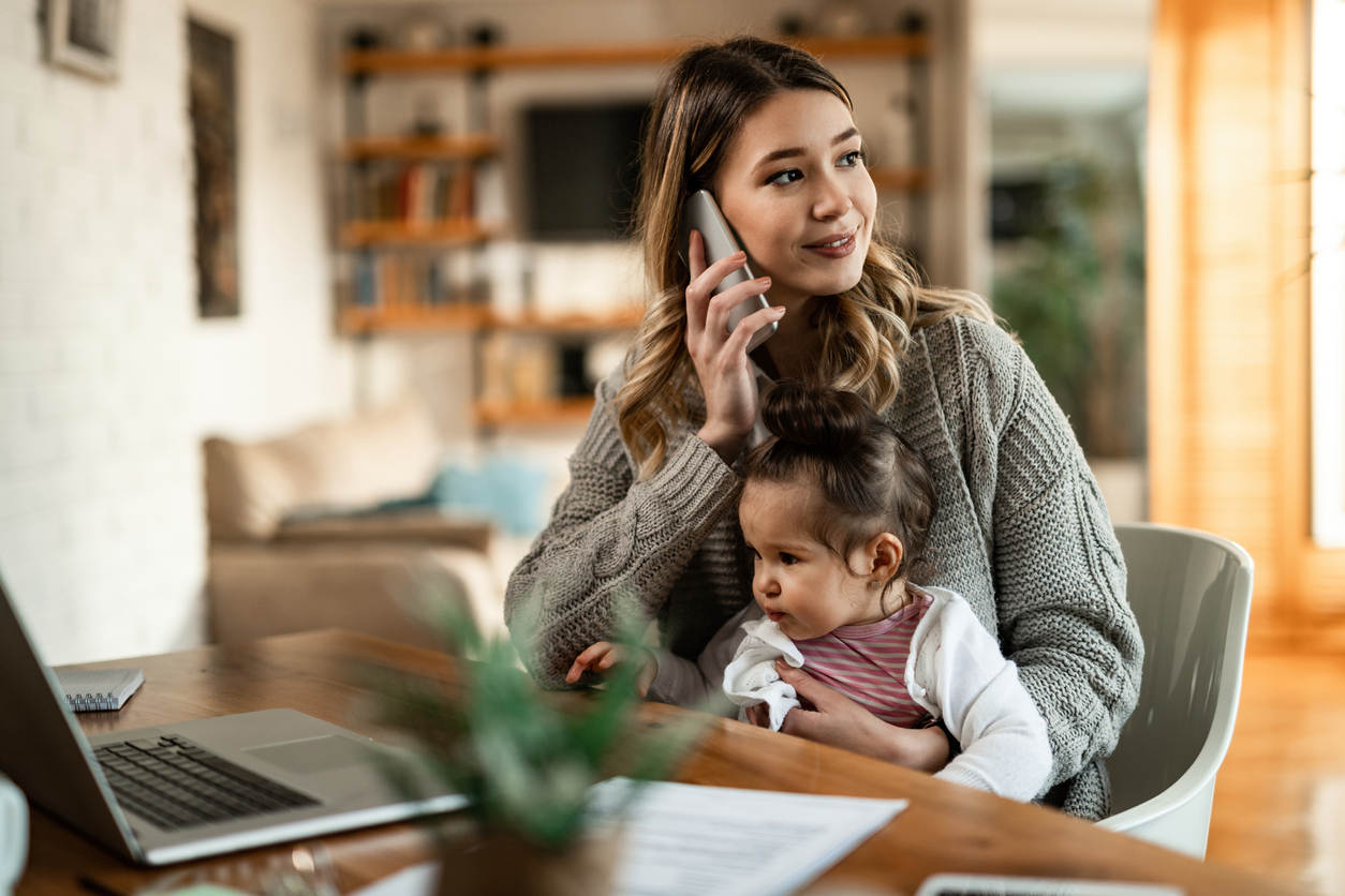 Mother holding daughter while talking on the phone